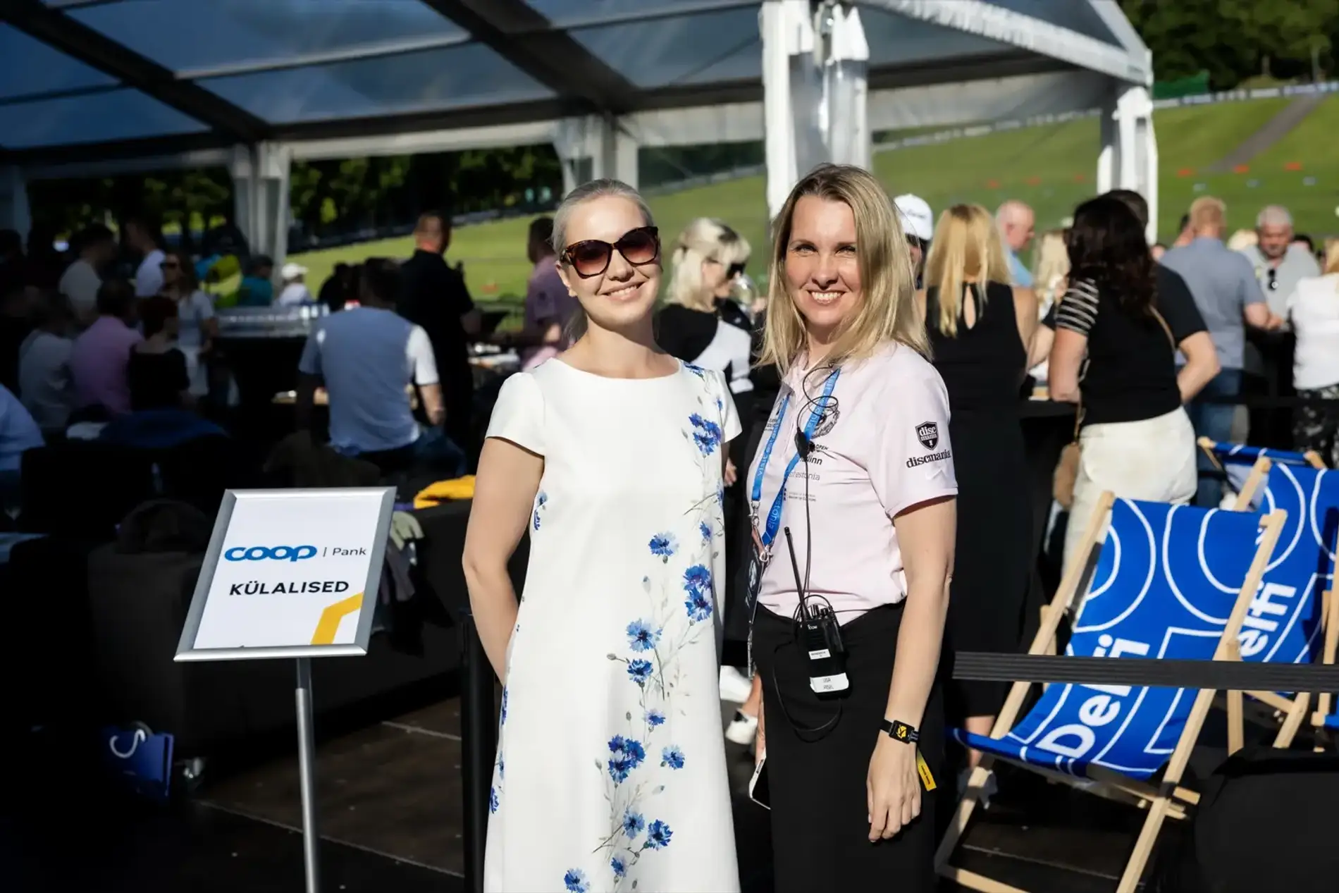 Guests in the Delfi VIP area, lanyards on, the course behind them